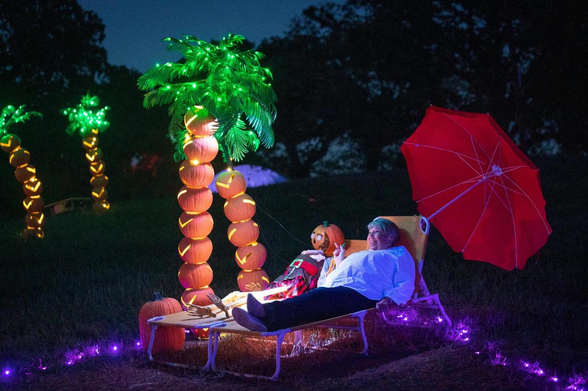 On a walkthrough with her grandchildren, Shirley Gulick poses with a pirate skeleton during Pumpkin Nights at Howell Farms in Arlington, Texas, on Thursday, Sept. 29, 2022. The event showcases thousands of pumpkins and features food vendors, fire dancers, a psychic and more.