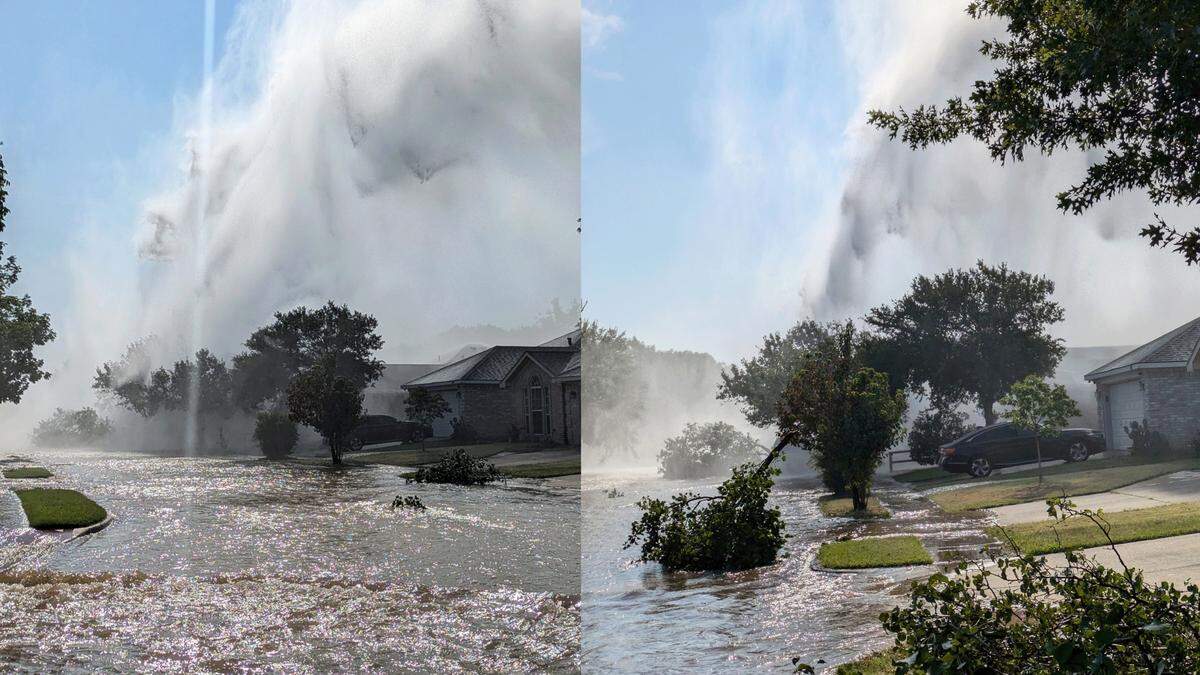 A geyser of water shooting up in a residential suburban street 