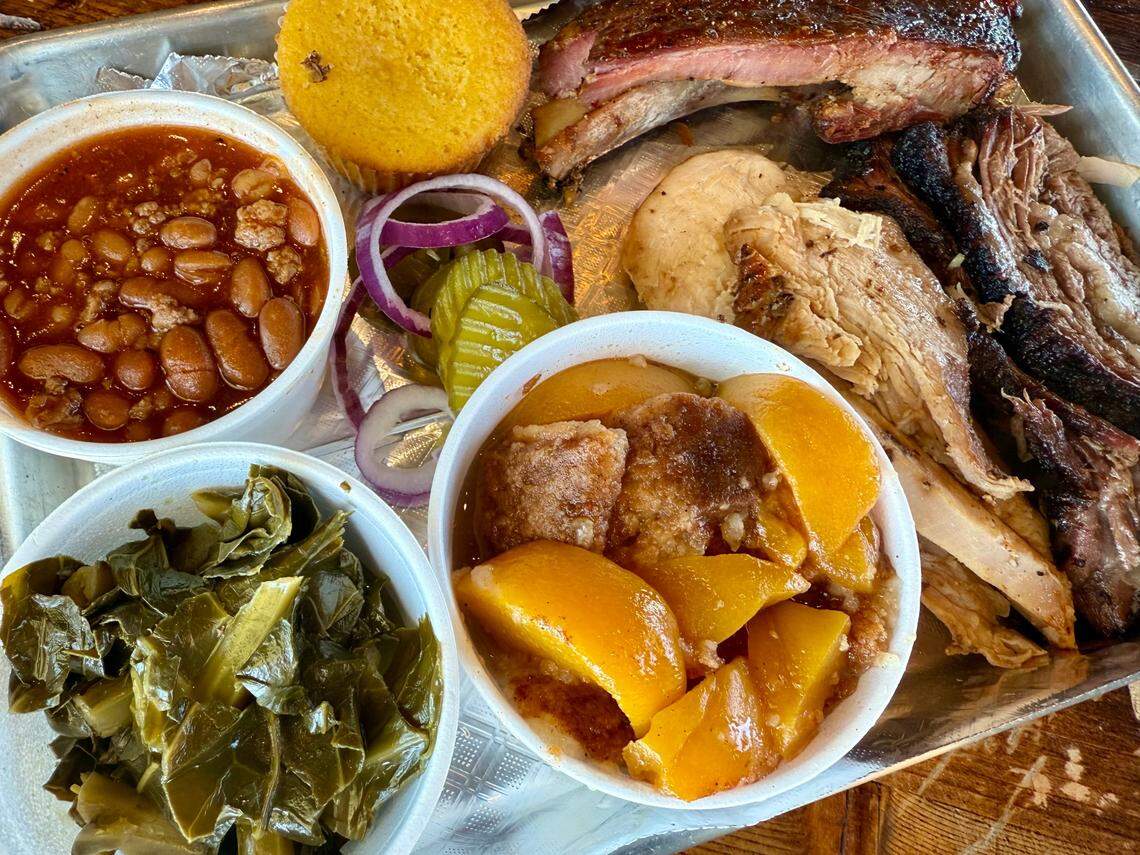 A three-meat combination plate at Lil JJ’s Smokehouse in Fort Worth Feb 23, 2025, with ribs (top), brisket (far right), turkey, baked beans, collard greens and peach cobbler. The restaurant is the former Berry Best BBQ.