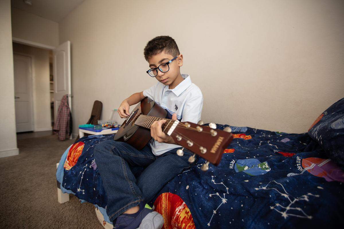 Ryan Ben Alaya, 11, plays his guitar in his room on Tuesday, Dec. 16, 2025.