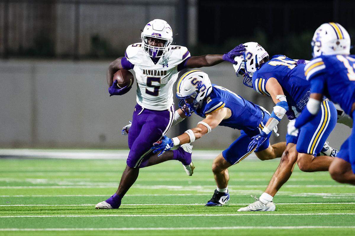 Alvarado running back Demarcus Belton sticks his arm out toward a Sulphur Springs defensive player while running with the ball in a Class 4A Division I area playoff game Friday.