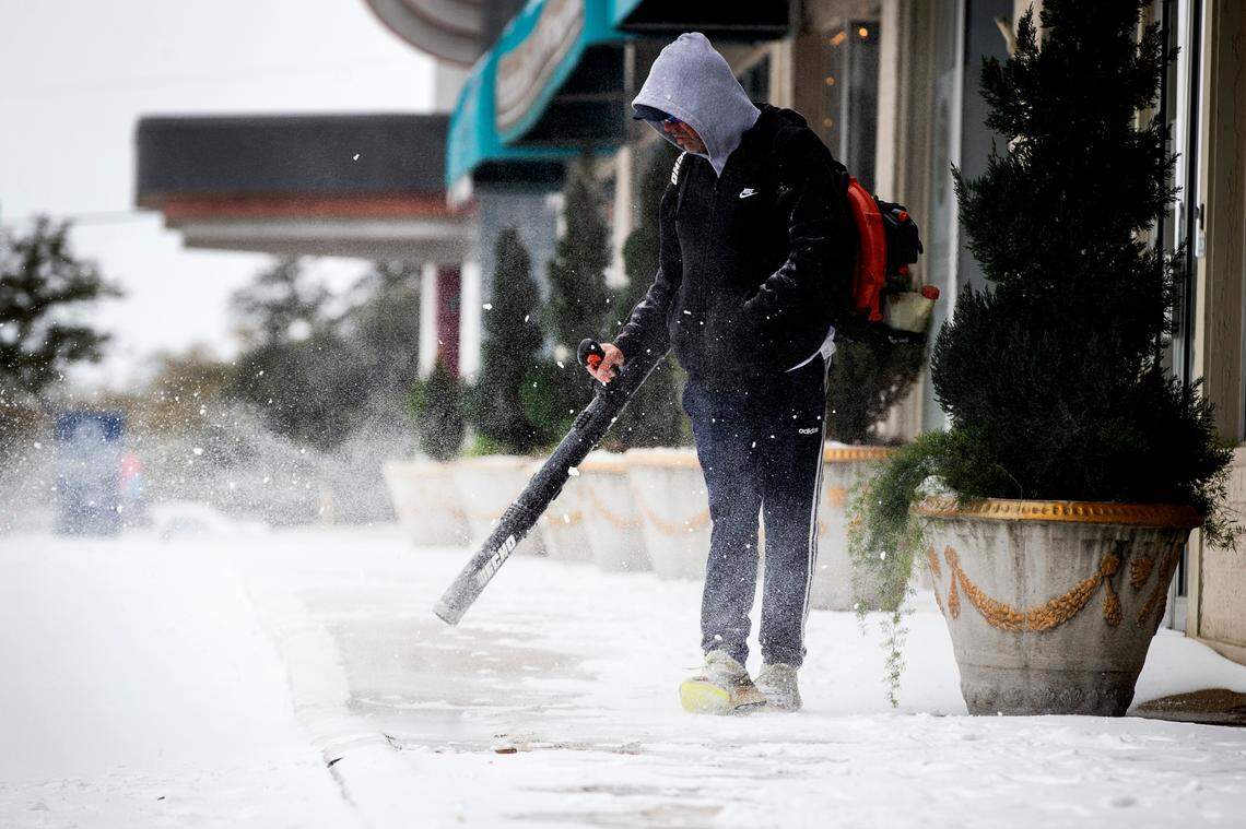 Scott Blocker uses a blower to clear the sidewalks in front of a shopping center on Camp Bowie Blvd. on Feb. 17, 2021, in Fort Worth.