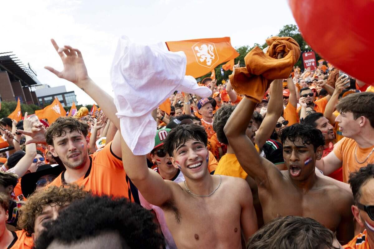 Netherlands soccer fans dance in the streets as the Orange Bus arrives to Dallas Stadium ahead of the FIFA World Cup match against Japan on Sunday, June 14, 2026 in Arlington, Texas.