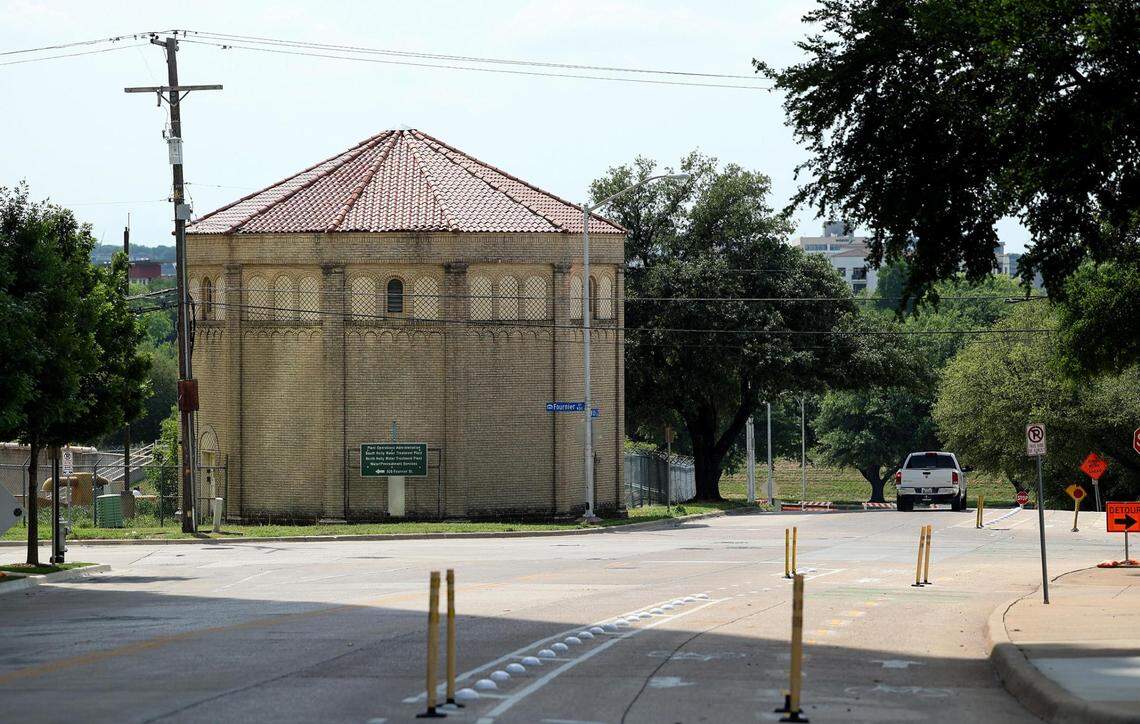 A round brick building with a red tile roof is on the left side of a curving street.