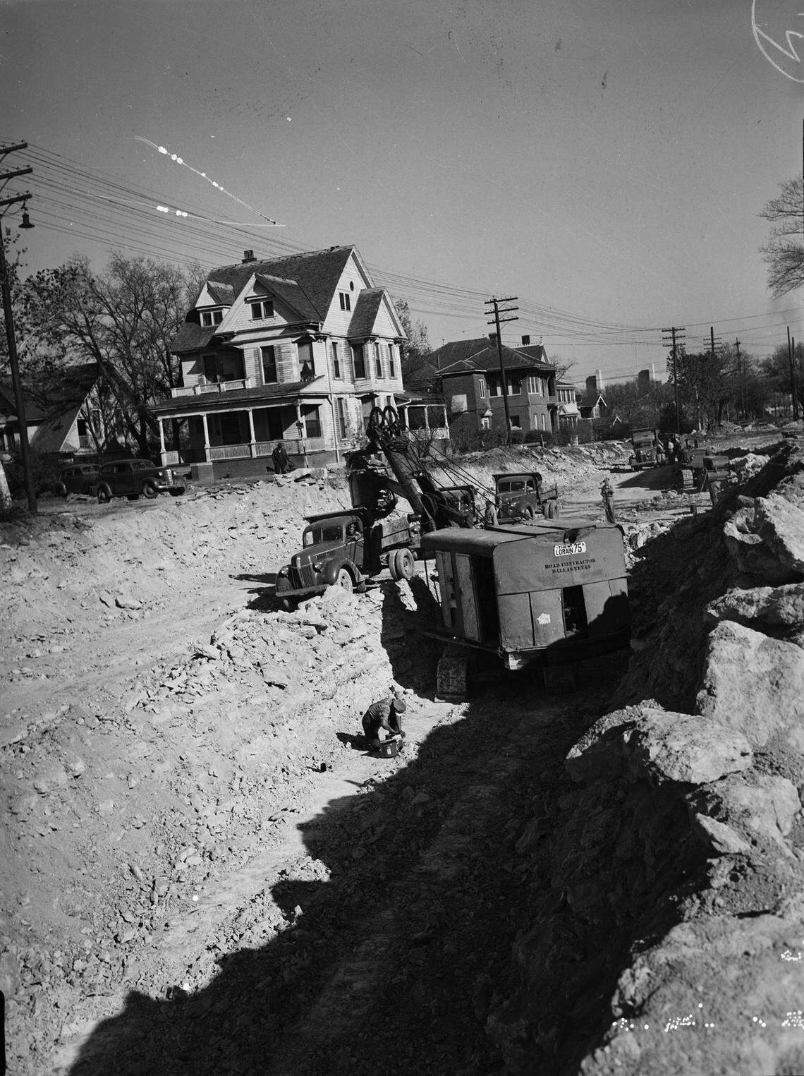 Dec. 3, 1941: A large power shovel digging out rock and loading it in trucks after workmen blasted dynamite at the West Lancaster Avenue bluff for a cut and fill project that will connect Trinity River Bridge with Summit Avenue. Standing around the power shovel are a few construction workers and some parked cars.