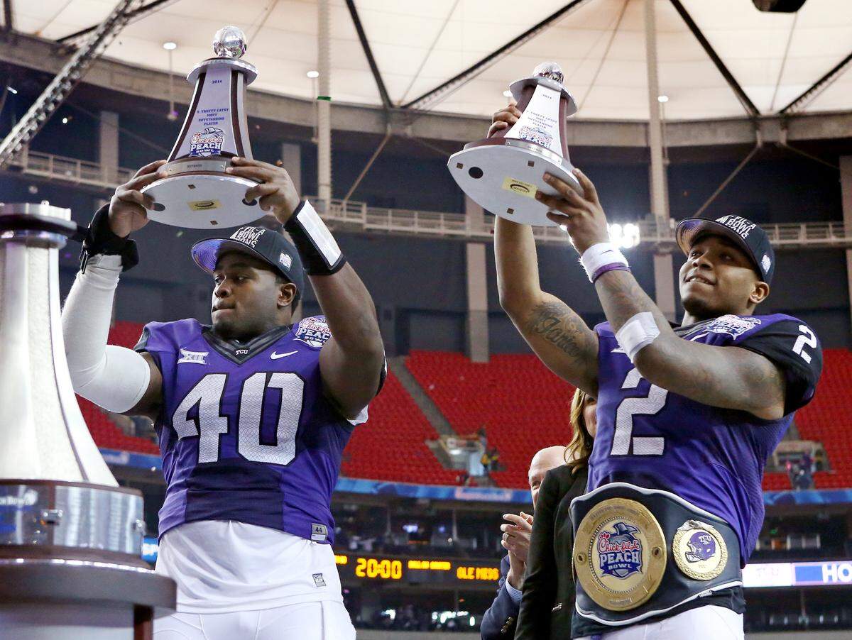 TCU Horned Frogs MVP defensive and offensive players, defensive end James McFarland (40) and quarterback Trevone Boykin (2) raise trophies after TCU beats the University of Mississippi 42-3 to win the 2014 Peach Bowl in Atlanta, Georgia, Wednesday, December 31, 2014.