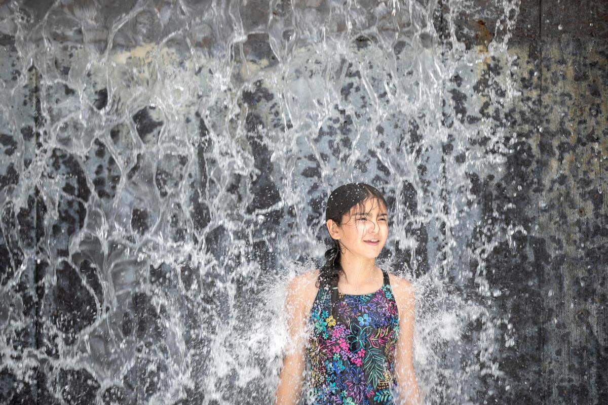 Mary Spoon, 11, of Fort Worth, stands under a waterfall in the splash park at the Fort Worth Zoo on Wednesday, June 8, 2022.
