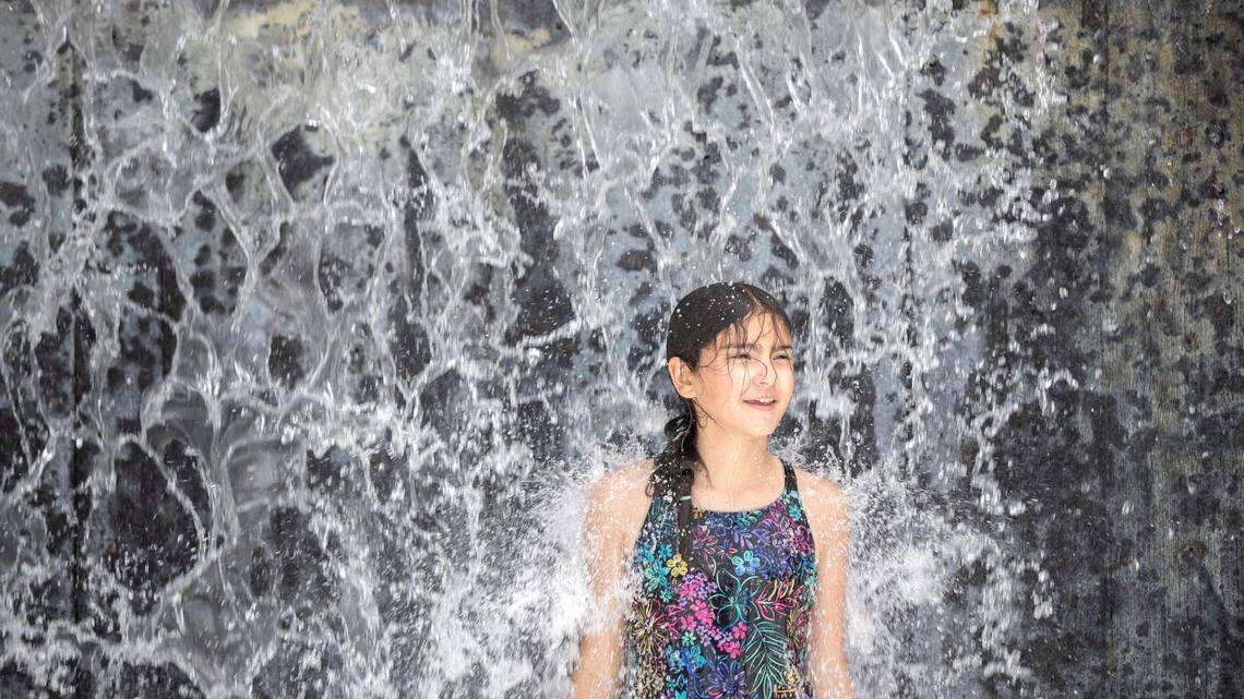 Mary Spoon, 11, of Fort Worth, stands under a waterfall in the splash park at the Fort Worth Zoo on June 8, 2022.