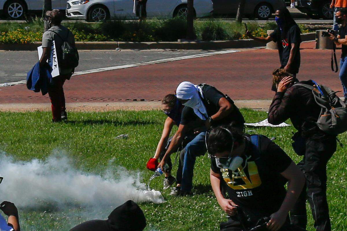 Demonstrators pour water May 30 to defuse a tear gas canister shot by police in front of Dallas City Hall. The demonstrators protested police brutality following the death of George Floyd while he was being arrested by Minneapolis police.