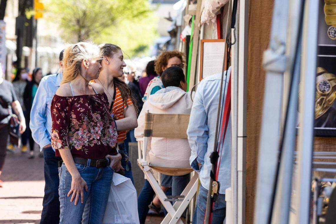 Festival goers check out art in booths during the Main Street Fort Worth Arts Festival on Thursday, April 7, 2022, in downtown Fort Worth.