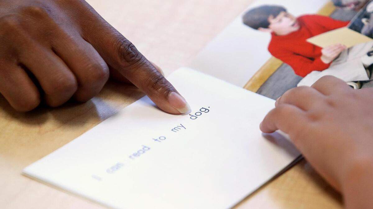 Tequila Lockridge, una intervencionista de alfabetización nivelada en el Centro Politécnico de UCC, ayuda a Jonathan Soto, de 8 años, a pronunciar una palabra mientras lee un libro, el 13 de julio de 2021, en Fort Worth. United Community Centers organizó un programa de alfabetización educativa de verano para hacer frente a las lagunas en la alfabetización debido a la pandemia del COVID-19.