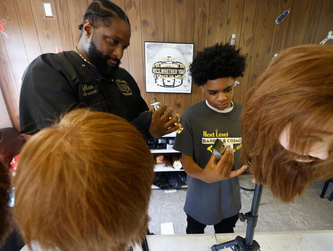 Owner of Luxury Grooming Lounge, TyRon Brown, gives Kayden Stuart, 13, tips on handling clippers at Next Level Barber and Cosmo camp in Fort Worth on Thursday July 10, 2025.