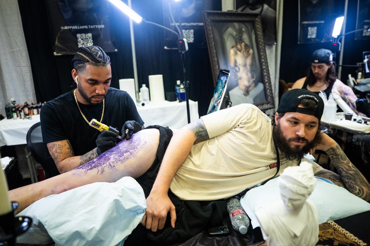 Tattoo artist Jeff Williams, left, works on a design for Fort Worth resident Josh Sprayberry, right, during Fort Worth Tattoo Arts Festival on Friday, June 7, 2024, at the Fort Worth Convention Center. Sprayberry, who enjoys monster movies, chose to get a design of “predator.”