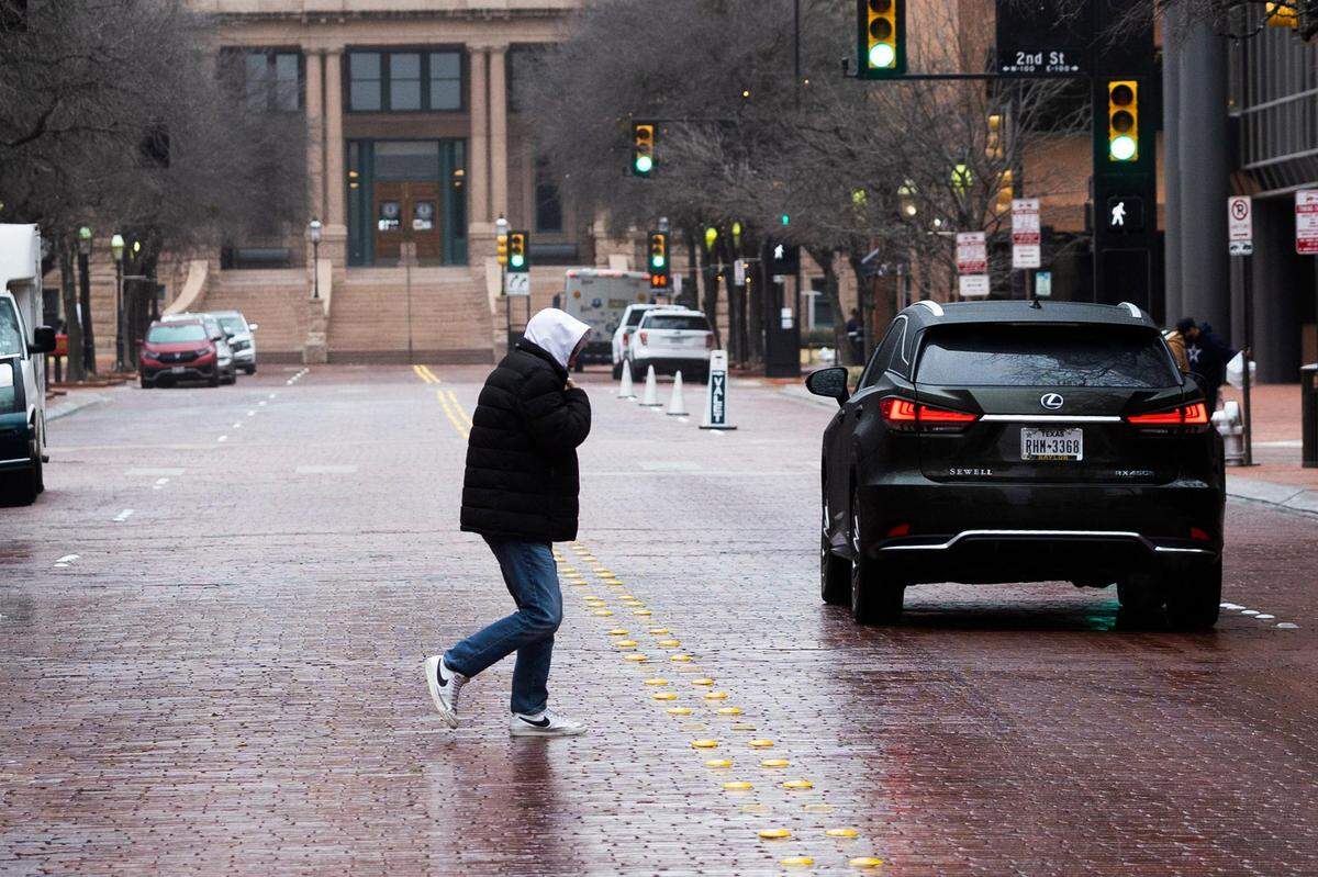 A person walks across Main Street as freezing rain falls across the region Wednesday, Feb. 23, 2022, in downtown Fort Worth.