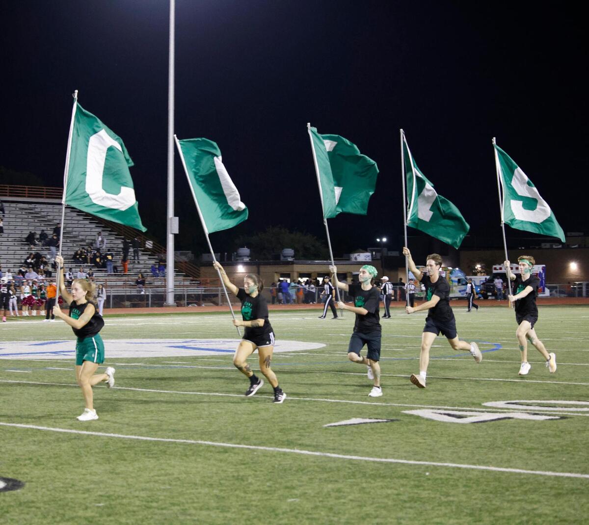 The Colts flag bearers run the field after a score during a District 8-6A football game at C.H. Wilemon Field in Arlington, Texas, Friday, Oct. 18, 2024.