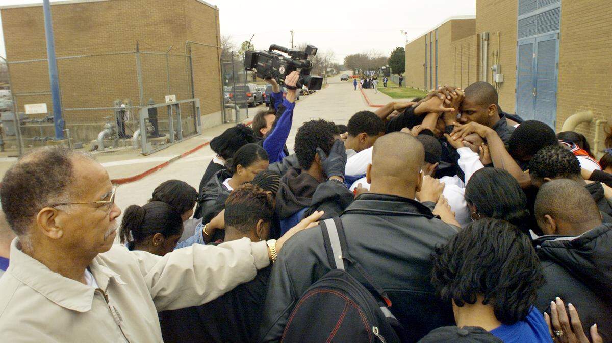 Coach Robert Hughes joins his team in a brief prayer before the Dunbar High School basketball team leaves for the state playoff tournament in Austin in 2003.