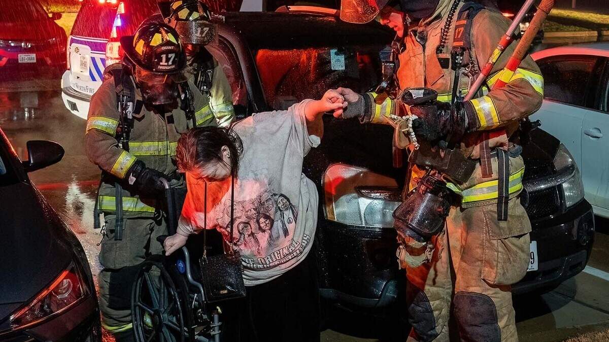 Fort Worth firefighters assist a resident at the scene of an apartment complex fire in the southwest part of the city on Wednesday morning.