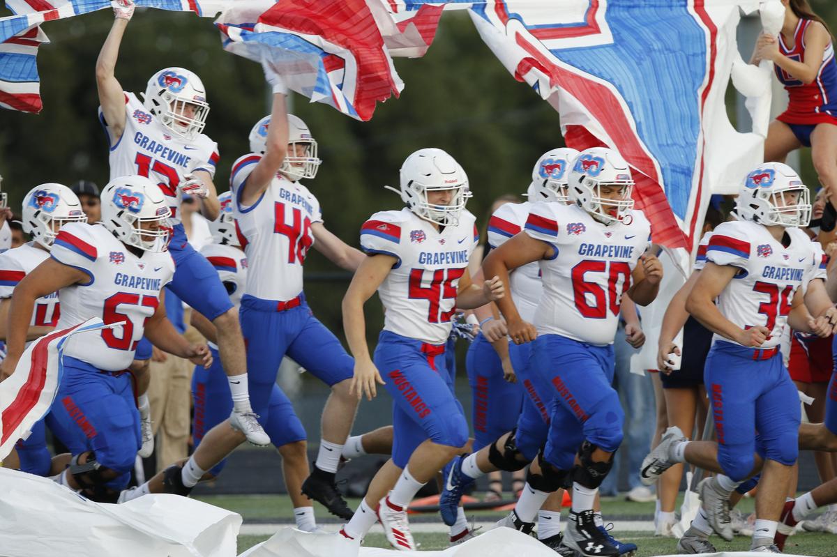Grapevine players romp through a banner before the game. The Grapevine Mustangs played the Axle Hornets on the opening night of Friday night football at Hornet Field in Azle, August 30, 2019.
