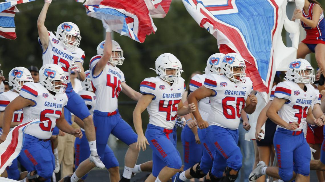 Grapevine players romp through a banner before the game. The Grapevine Mustangs played the Axle Hornets on the opening night of Friday night football at Hornet Field in Azle, August 30, 2019.