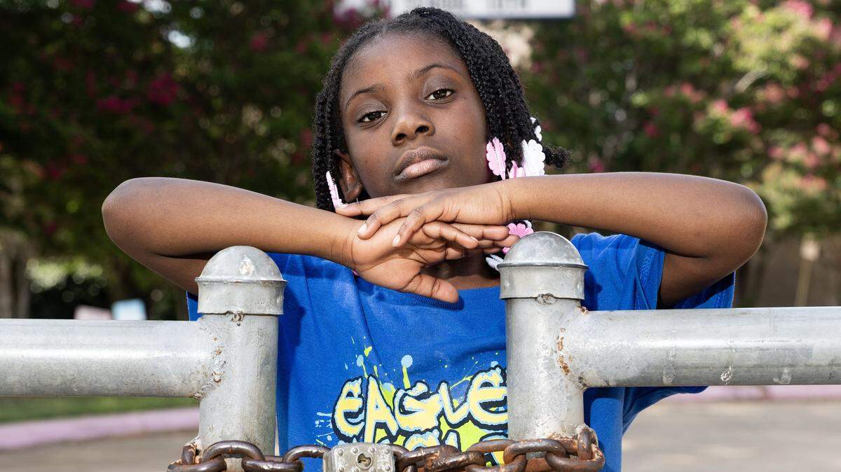Briscoe student Aniyah Lomax, 8, is photographed in front of the closed gate at Briscoe Elementary School in Fort Worth on Saturday, July 12, 2025. Briscoe is one of the multiple Fort Worth ISD schools chosen to close within the next few years.