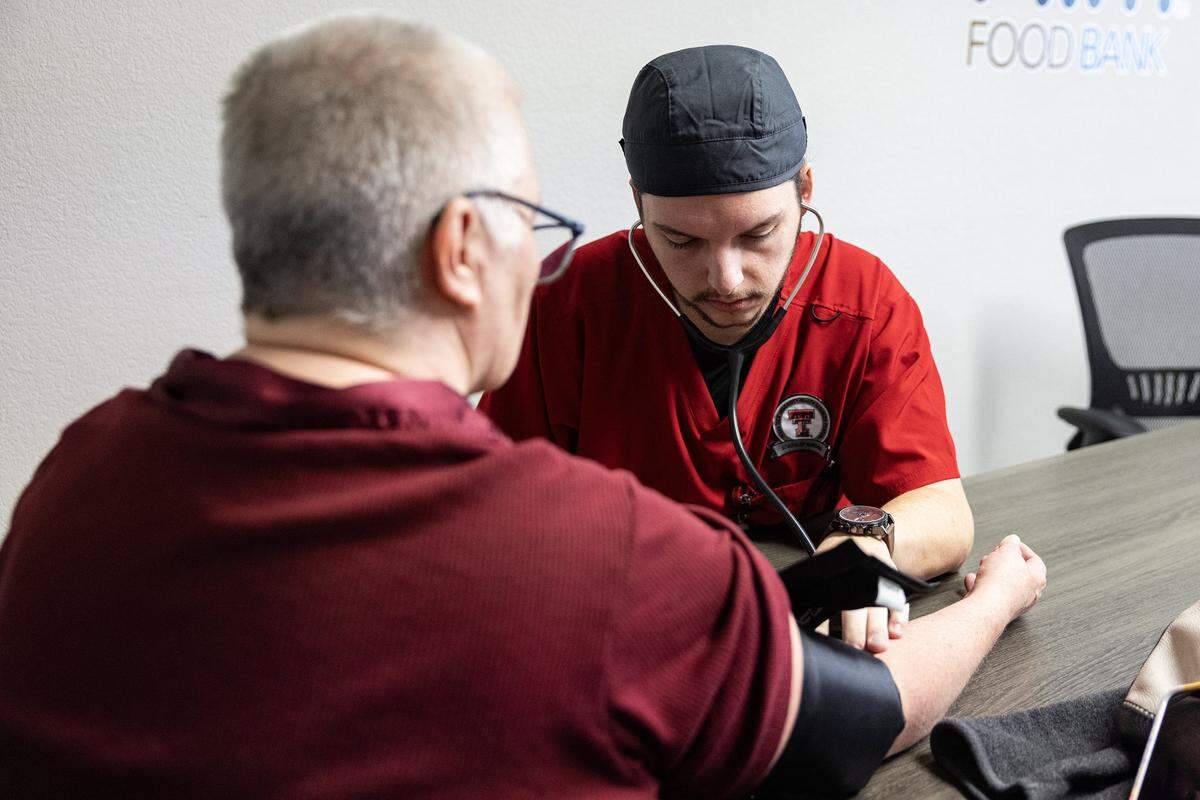 Nursing student Grayson Walker takes the blood pressure of Karen Gotch as part of the Wellness on Wheels program at Him Food Bank in Mansfield on Wednesday, Dec. 3, 2025.