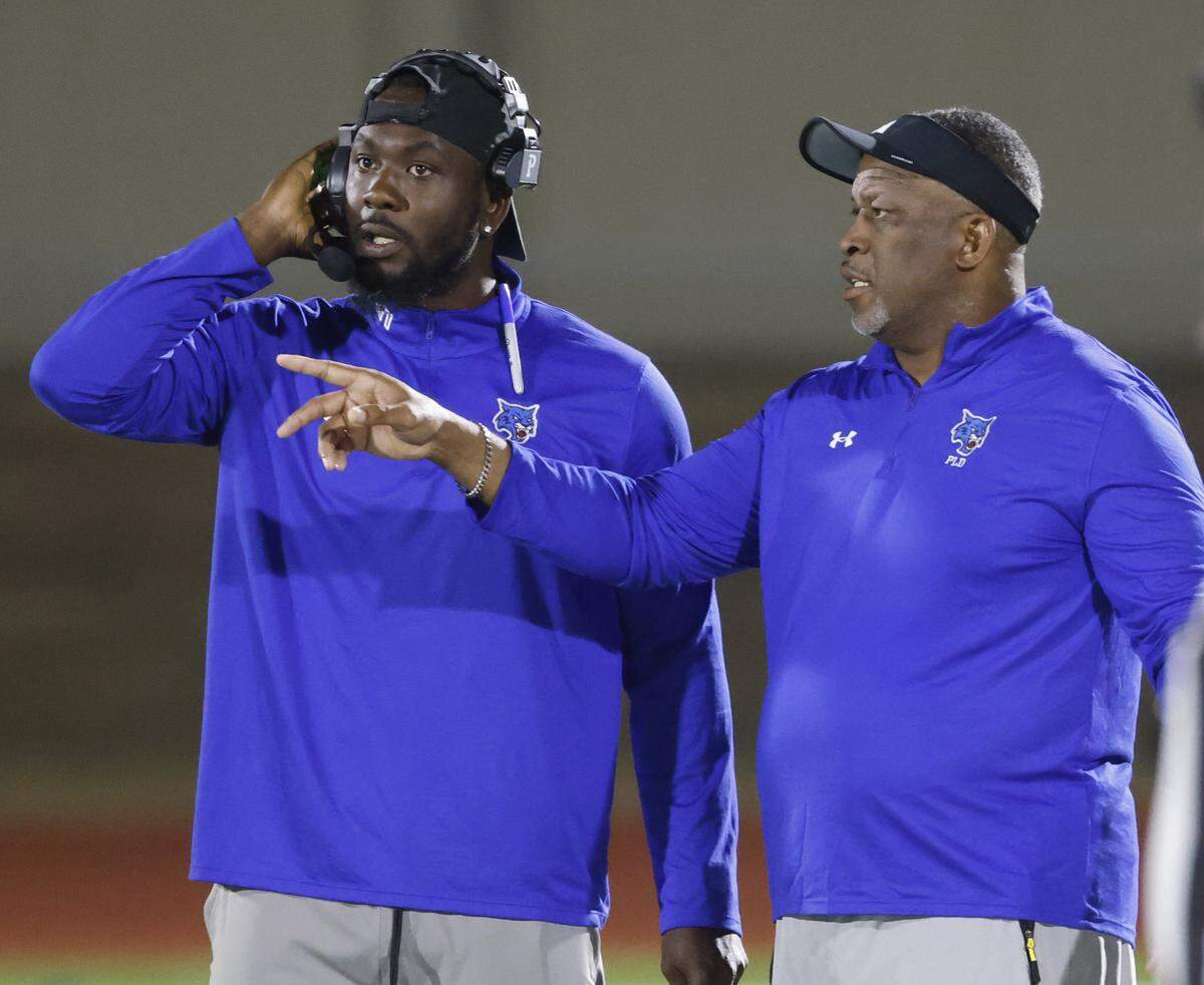 Dunbar head coach Todd Lawson talks to offensive coordinator Darius White during the first half of a UIL football game between Benbrook and Dunbar at Herman E. Clark Stadium in Fort Worth, Texas, Friday, October 10, 2025.