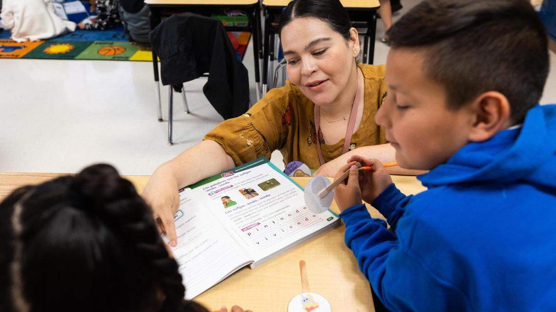 Teacher Maria Andrade helps Nicholas Lugo and Alayna Suarez with work during a second grade bilingual class at M. H. Moore Elementary in Fort Worth in this 2022 file photo.