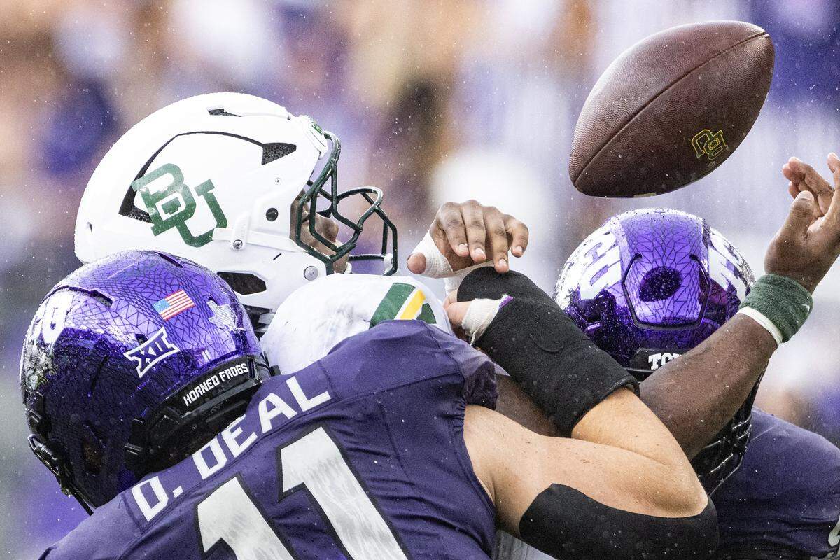TCU linebacker Devean Deal (11) and defensive end Chad Woodfork (9) force a fumble on Baylor running back Bryson Washington (7) in the first half of a Big XII football game between the TCU Horned Frogs and the Baylor Bears at Amon G Carter Stadium in Fort Worth on Saturday, Oct. 18, 2025.