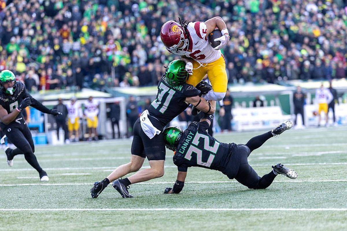 EUGENE, OREGON - NOVEMBER 22: Makai Lemon #6 of the Southern California Trojans is tackled by Dillon Thieneman #31 of the Oregon Ducks and Jadon Canady #22 of the Oregon Ducksin the first half against the Oregon Ducks at Autzen Stadium on November 22, 2025 in Eugene, Oregon. (Photo by Tom Hauck/Getty Images)