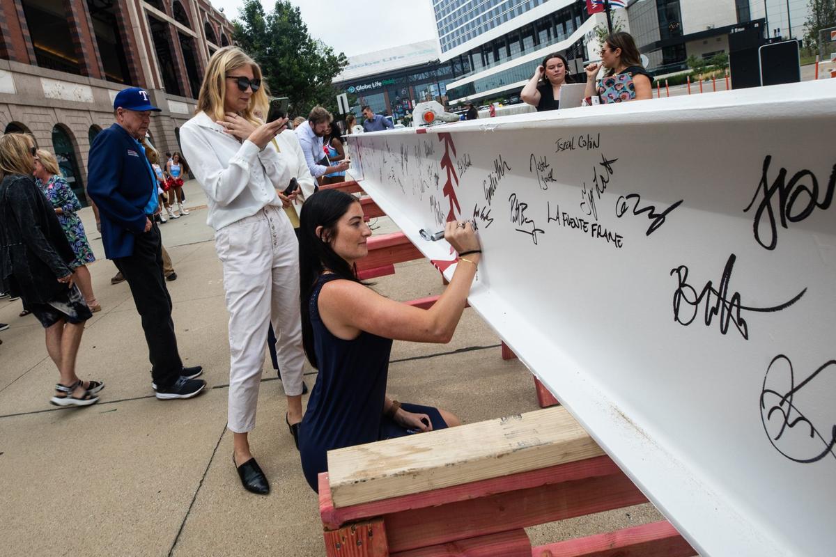 Arlington resident Kylie Robbins signs the beam during the topping off ceremony on Monday. Attendees signed their name on the beam as a celebration to the near competition of the building