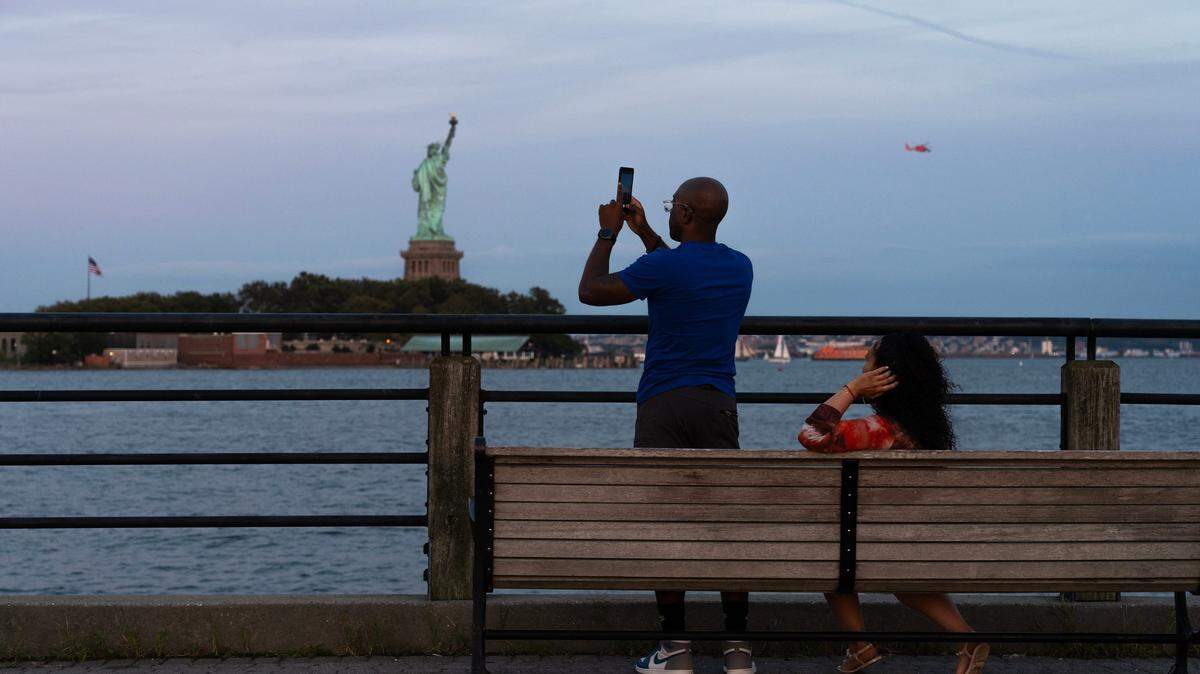 Oluyemi Carrington, of Jersey City, takes a photo on Lower Manhattan at the Statue of Liberty at sunset just before the rise of the Super Blue Moon at Liberty State Park in Jersey City, NJ on Wednesday Aug. 30, 2023.