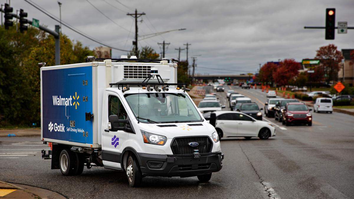 A four-wheel autonomous delivery truck crosses an intersection full of cars without any driver in the front seat.
