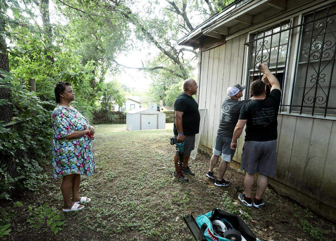 Lanell Hayward Harris, left, watches as members of the Fort Worth Police Department, including Chief Neil Noakes, installs an air conditioning unit in her southeast Fort Worth home on Thursday, July 15, 2021. Members of the police department are working to engage with the public and learn what needs a neighborhood might have as part of the #FortWorthSafe initiative.