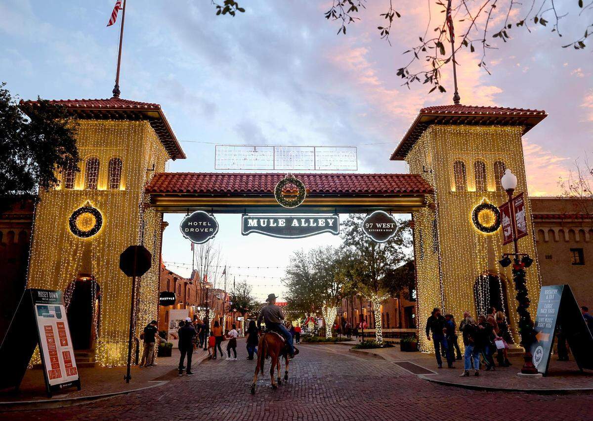 Rickey Hess rides Nellie onto Mule Alley in the Fort Worth Stockyards on a Friday night, December 10, 2021. The opening of the Hotel Drover and other restaurants and attractions along Mule Alley have drawn regional tourists to the location.