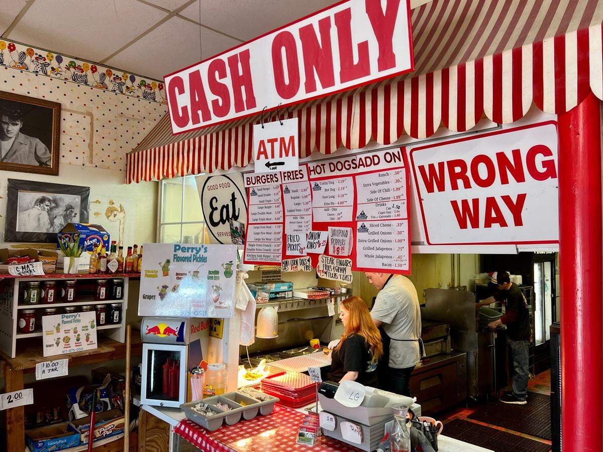 Signage is plentiful in front of workers Hailey and Cody Medford at Clown Burger in Haltom City May 18, 2023.