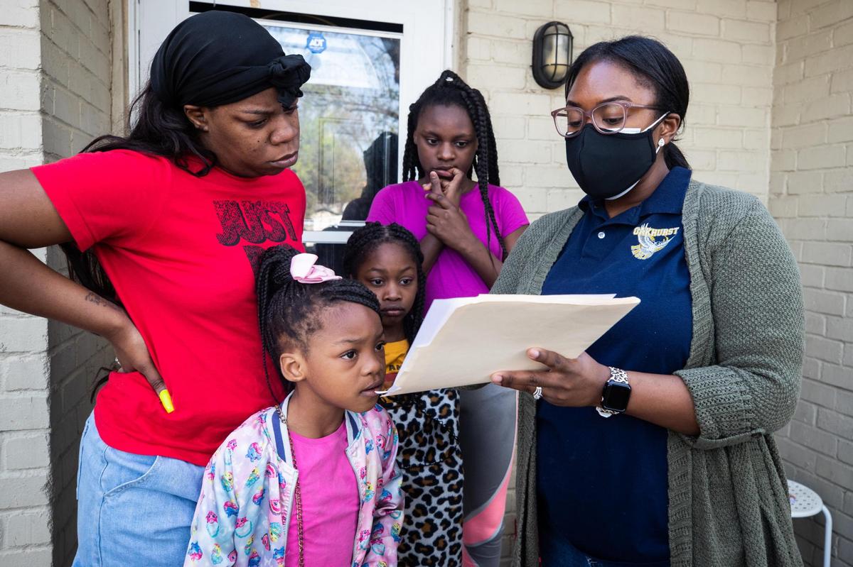 LaShun Cabness, a family and community partnership manager at Oakhurst Elementary School, right, shows Roberneshia Johnson and her children how to find their assignments Wednesday, March 24, 2021, in Fort Worth.