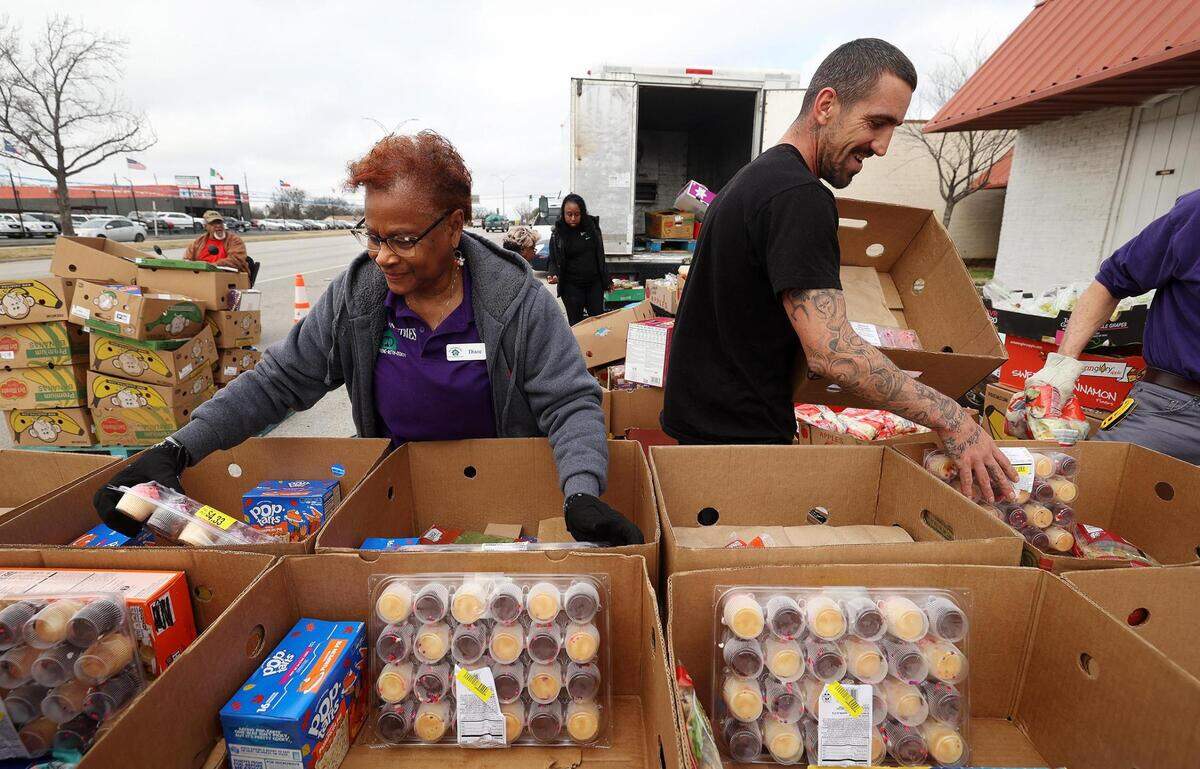 Diane Moore, board president and acting executive director of Eastside Ministries, left, and William Gibbs sort food into boxes to distribute to clients on Friday, February 2, 2024, in Fort Worth. The nonprofit converted to a drive-through method for food distribution after in late November heavily damaged their food pantry area. A suspect has been arrested on charges of arson. Moore said that many people prefer the new method, especially that food is given out every weekday instead of once a month.
