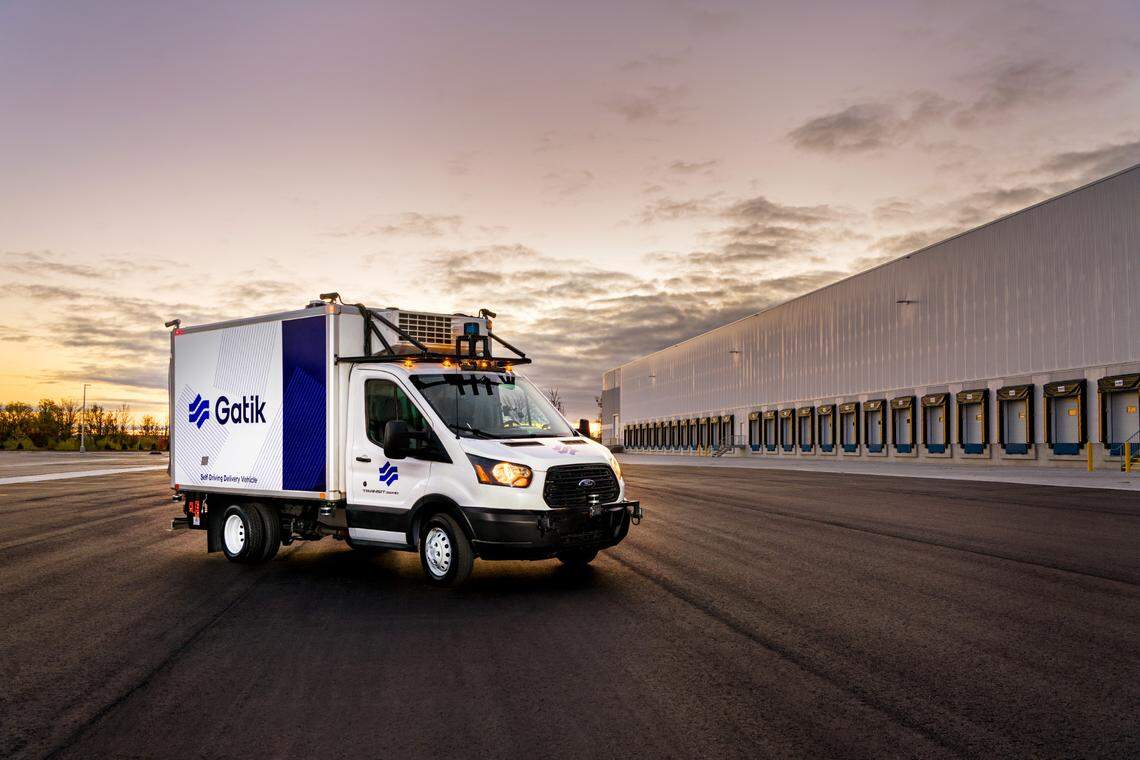 A four-wheel self-driving truck sits parked against a sunset.
