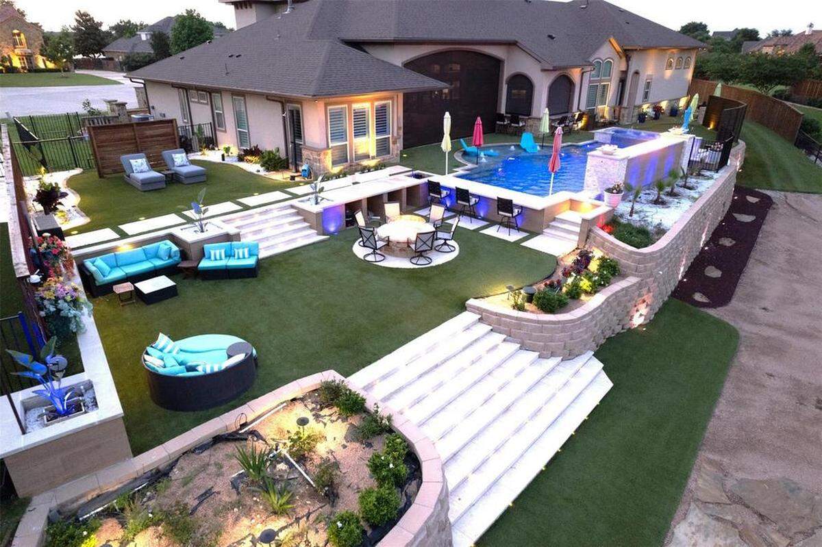 Backyard of home at Eagle Mountain Lake Resort: fake turf grass, an outdoor shower, pool with bar, putting green, and boat doc.