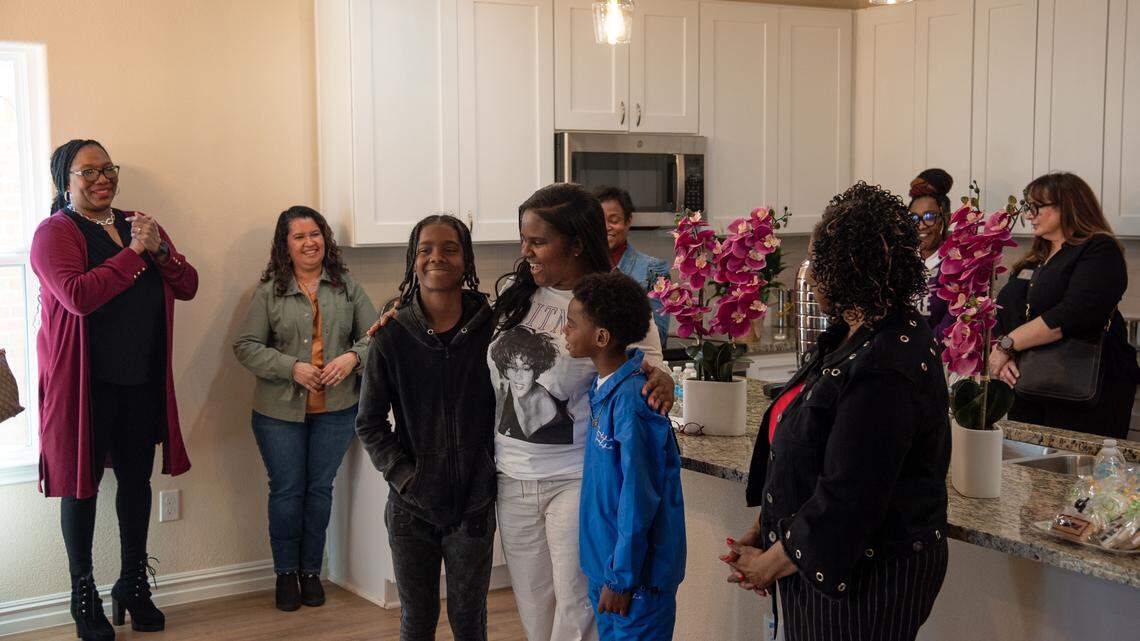 Amber Sanders flanked by her two boys, Zion (13) and Kingston (10), in the dining room of their new home during a ribbon-cutting ceremony Feb. 13. Sanders was able to purchase her first house with a federal housing voucher.