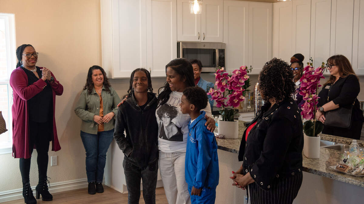Amber Sanders flanked by her two boys, Zion (13) and Kingston (10), in the dining room of their new home during a ribbon-cutting ceremony Feb. 13. Sanders was able to purchase her first house with a federal housing voucher.