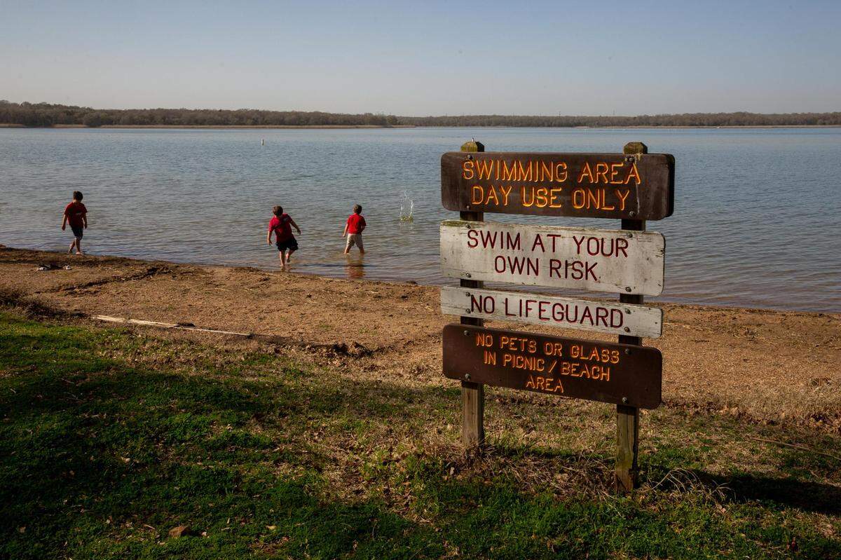 Children collect seashells and attempt to skip rocks from the bank of Fairfield Lake at Fairfield Lake State Park on Feb. 27, 2023. The park was open to the public for 50 years, but was located on leased land.