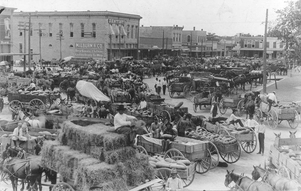 August 1920: Weatherford, Texas, street scene; carts and horses, people buying produce from farmers.