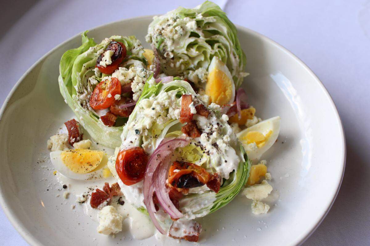 Crisp American wedge salad is a steakhouse staple, served with eggs, tomato, red onion and blue cheese dressing at Theodore’s Steak and Seafood.