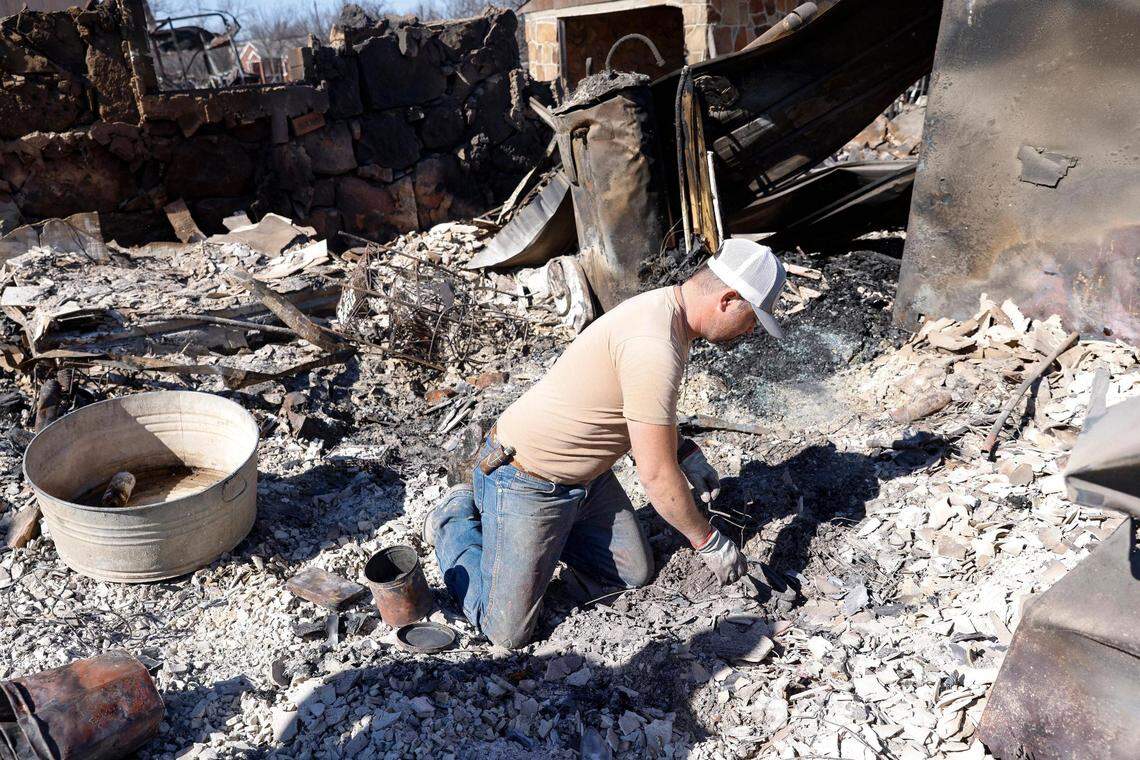 Seth Griffin sorts through the ashes of his mother’s home searching for coins they collected together on Saturday, March 19, 2022, in Carbon, Texas. The Eastland Complex fire has spread over more than 50,000 acres across western Texas.