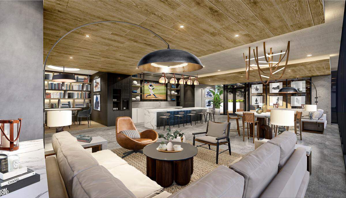 A rendering of the demonstration kitchen shows a long dining table, a large couch, accent chairs, a bar counter facing a television and modern art.