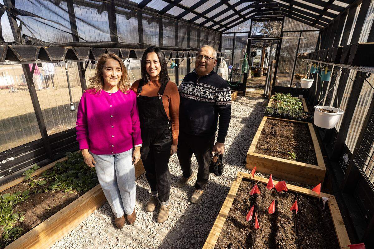 Luzmiryam, left, and Luis Rojas, right, are photographed with their daughter and founder of Curious Farmhouse, Lizned Larrota, center, at the greenhouse in Godley on Wednesday, Dec. 10, 2025. The Curious Farmhouse is a nature-based, bilingual space where children learn farming, nutrition and hands-on skills through gardening.