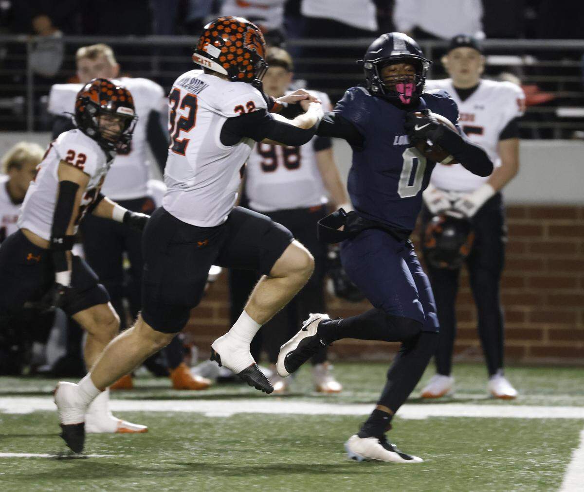 Frisco Lone Star running back Davian Groce (0) outruns Aledo linebacker Chase Wilburn (32) for yards during the first half of a UIL Class 5A Division I Semifinal on Friday Dec. 12, 2025 at Vernon Newsom Stadium in Mansfield, Texas.