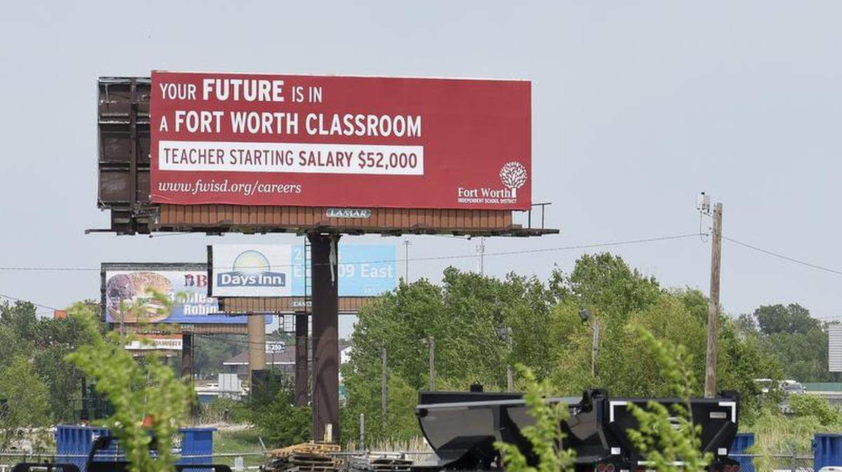A sign north of State Highway 9 on the west side of Interstate 35 near Norman, Okla., beckons Oklahoma teachers to Fort Worth, Texas, with the promise of higher pay, Wednesday, May 9, 2018. (Kyle Phillips/The Norman Transcript via AP),
