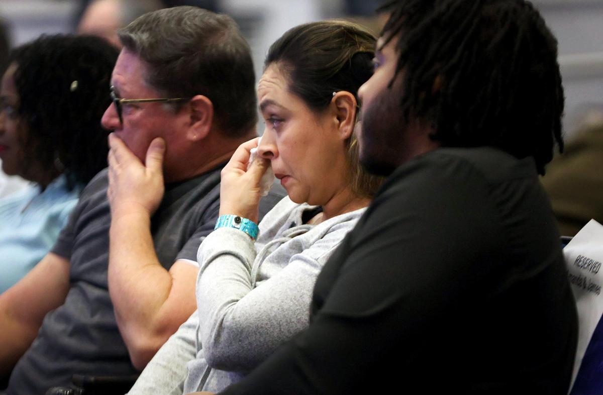 The couple is seated, and she is wiping a tear as they watch the video.
